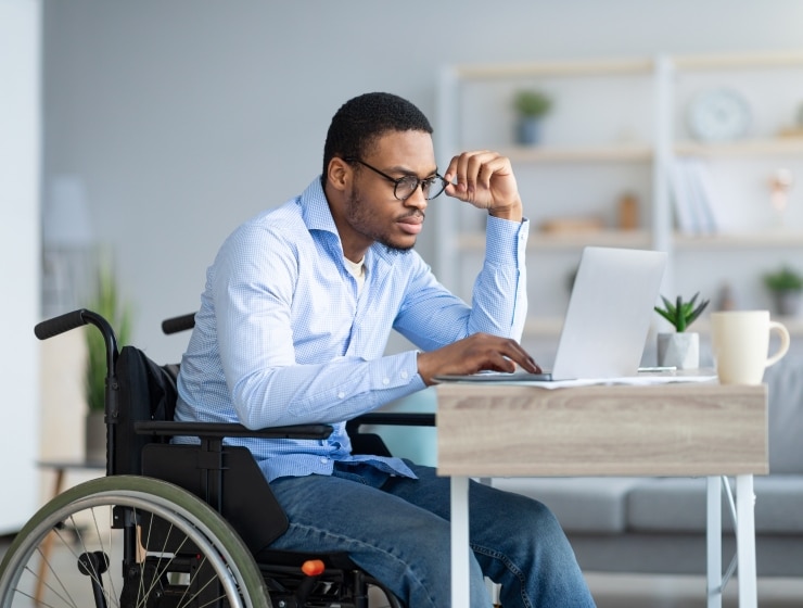 Un homme en fauteuil roulant travaillant sur un ordinateur en télétravail